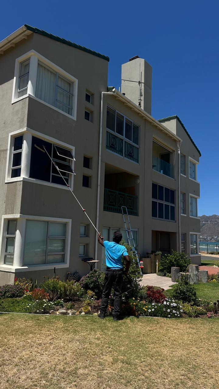 Blu cleaner working from the lawn to clean the upper windows of a Cape Town apartment block