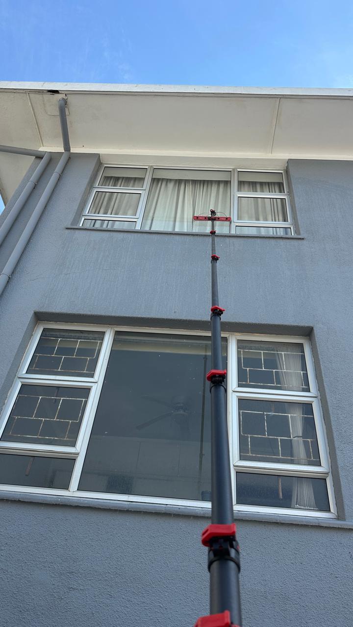 A long-reach brush cleaning the upper-floor windows of a Cape Town apartment block