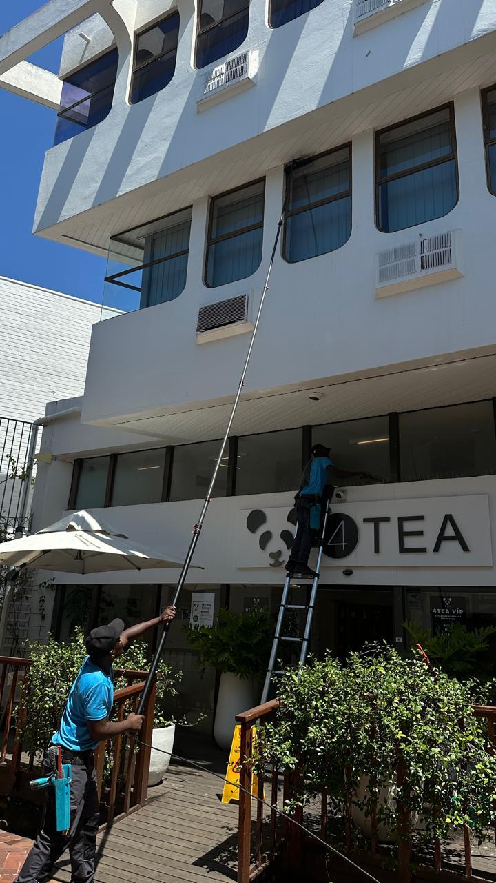 Blu cleaners washing the front windows of a cafe from the pavement