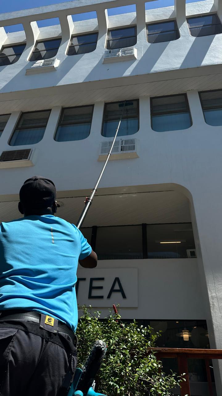 Blu cleaner washing the upper windows of a Cape Town cafe building from the pavement