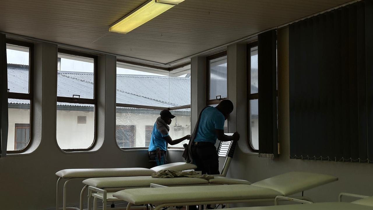 Two Blu cleaners washing the inside windows of a business