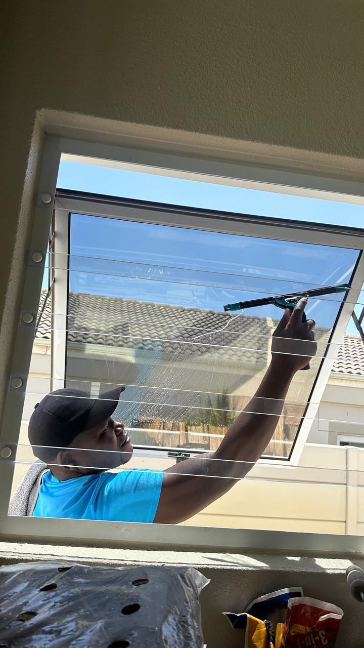 Technician squeegeeing an interior window with a mountain view behind