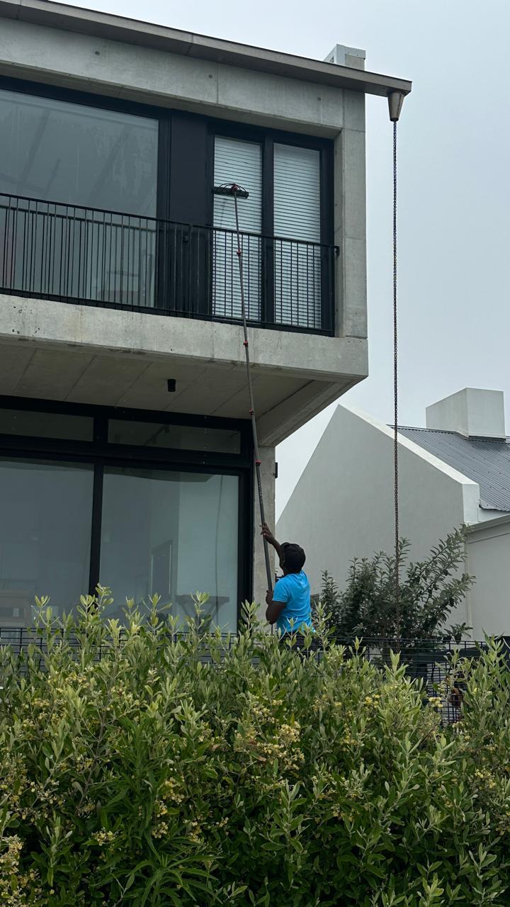 Blu cleaner washing the garden-side windows of a modern Cape Town home from the ground