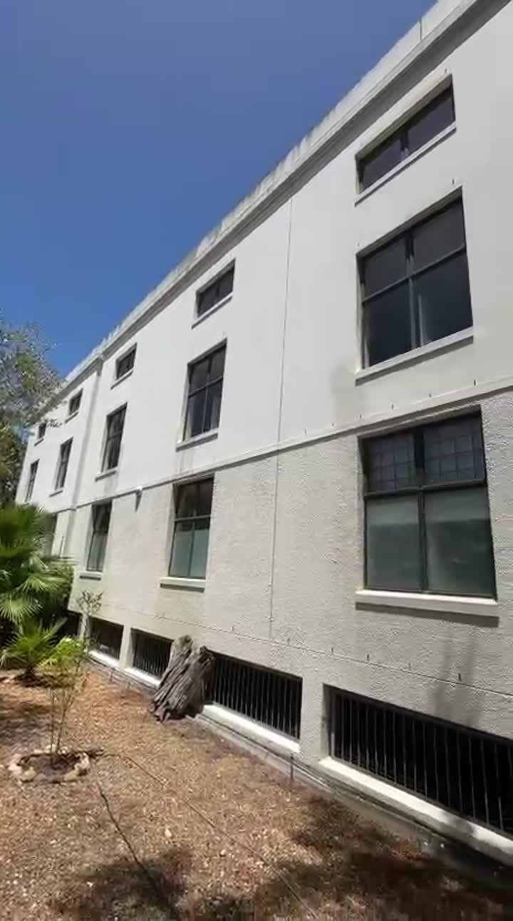The outside of a white apartment block with rows of windows