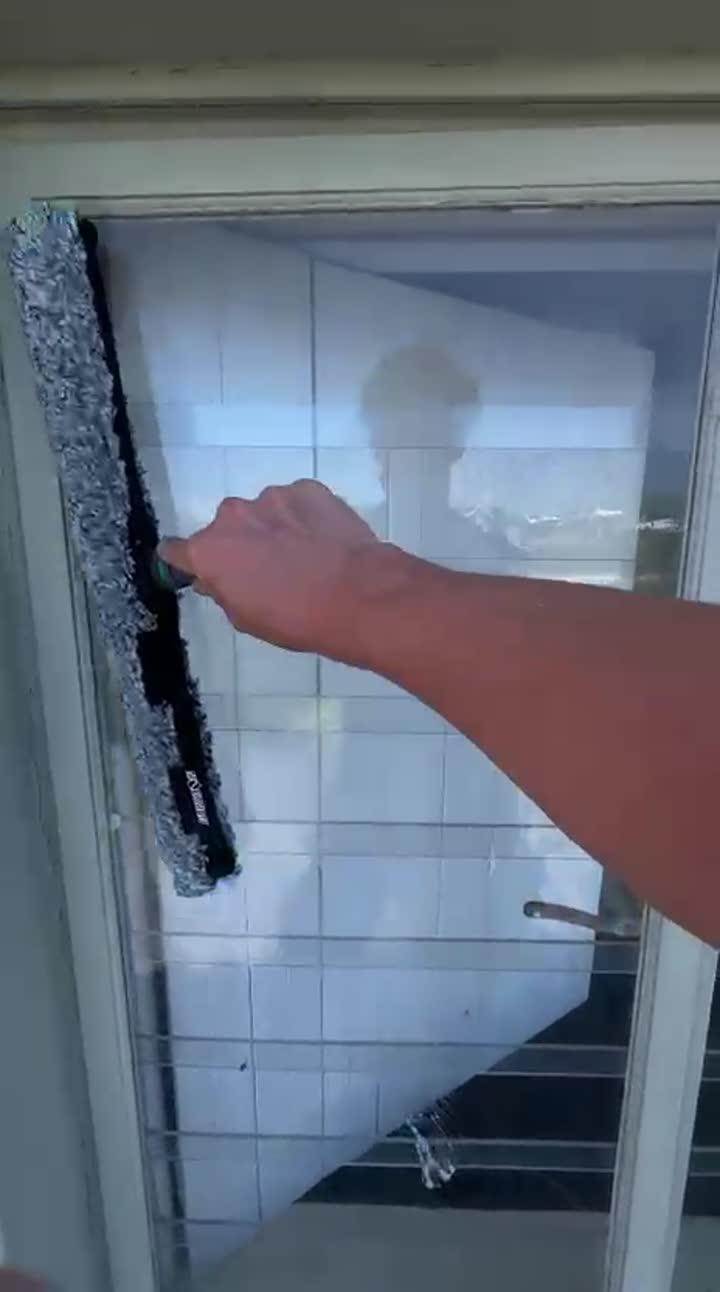 Blu cleaner washing a large glass door with a window mop